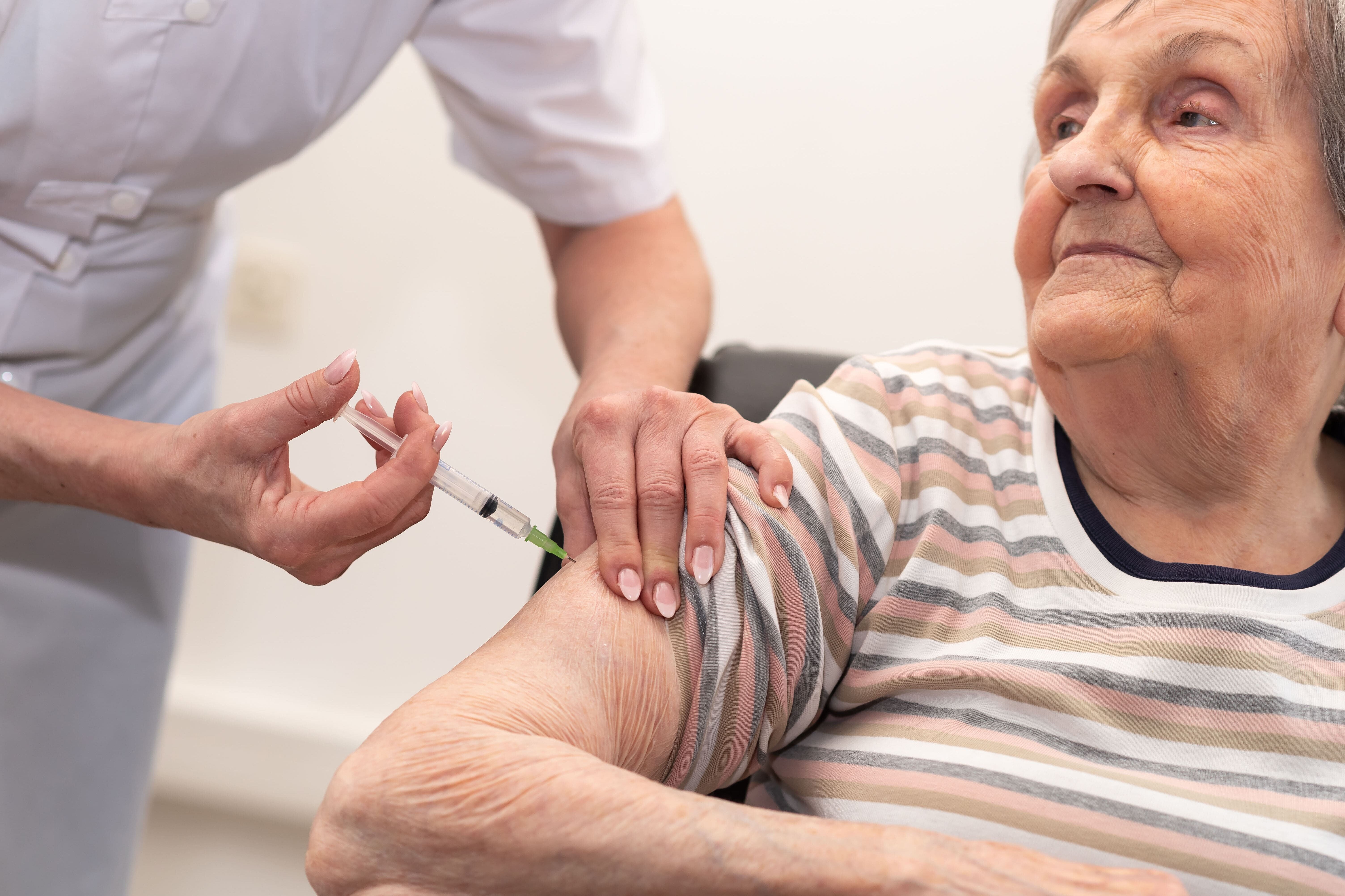 Elderly lady receives vaccination in the upper arm